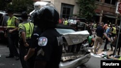 Nhân viên ứng cứu đầu tiên đứng bên cạnh chiếc xe bị tông khi một chiếc xe khác lao vào đám đông những người phản biểu tình tại một cuộc tụ tập ủa những người chủ trương thượng đẳng da trắng ở thành phố Charlottesville, bang Virginia, ngày 12 tháng 8, 2017