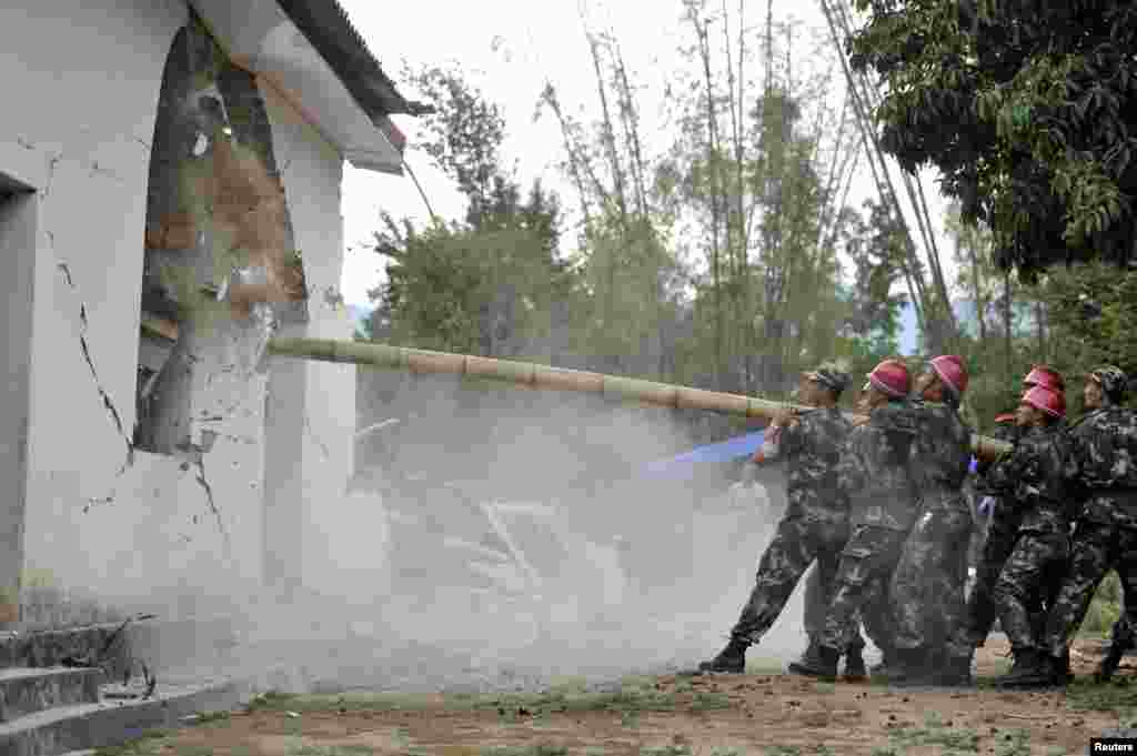 Paramilitary policemen demolish a building after an earthquake hit Yingjiang county, Yunnan province, May 24, 2014. At least 13 people were injured after a 5.6-magnitude earthquake jolted Yingjiang county in southwest China, Xinhua News Agency reported.