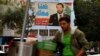 A street vendor stands in front of a poster of outgoing Prime Minister Saad Hariri that hangs on a street in Beirut, Lebanon, Nov. 6, 2017.