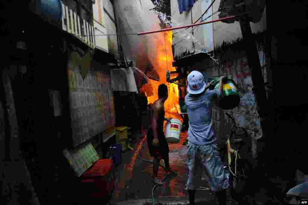 Người dân trong một khu nhà ở Manila, Philippines dùng chậu thau để chữa lửa.