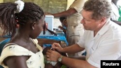 FILE - GAVI chief Seth Berkley inoculates a child with a Rotavirus vaccine at the in the village of Nkyenoa, Ghana, April 27, 2012.