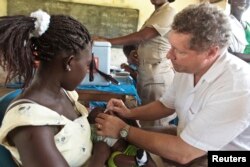 FILE - Chief executive of the Global Alliance for Vaccines and Immunisation (GAVI), Seth Berkley, vaccinates a child with a Rotavirus vaccine at the Nkyenoa health outreach point in the village of Nkyenoa April 27, 2012.