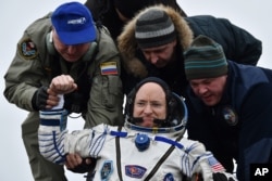 FILE - Ground personnel help International Space Station (ISS) crew member Scott Kelly of the U.S. to get off the Soyuz TMA-18M space capsule after landing near the town of Dzhezkazgan, Kazakhstan on March 2, 2016.