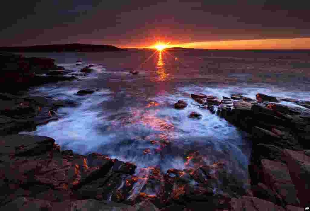 The sun&#39;s rays strike the rocky coast of Acadia National Park, in Maine, USA. 