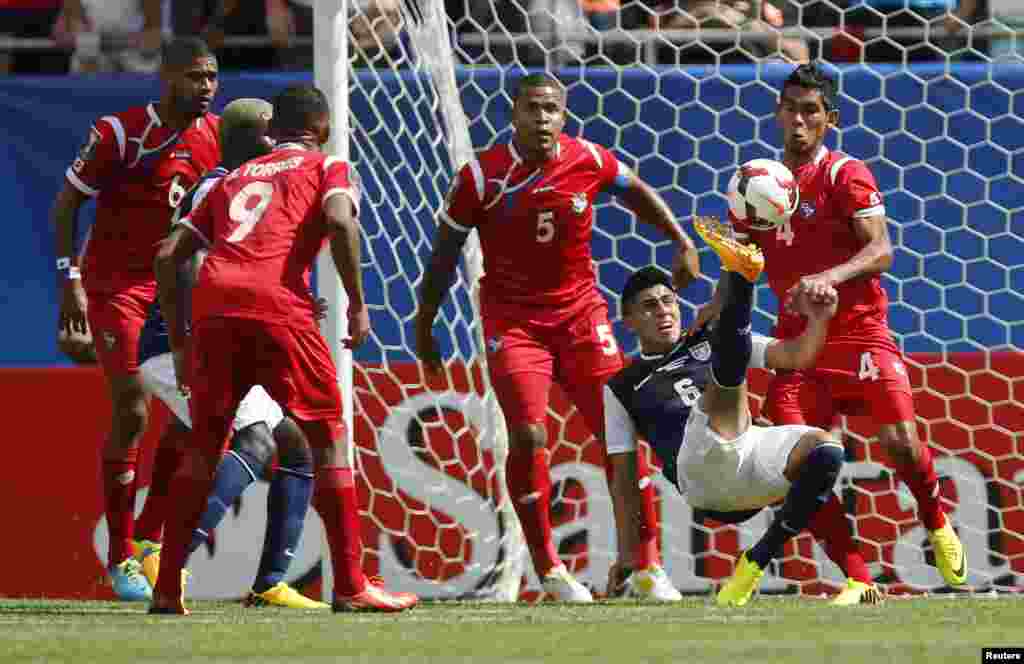 El delantero de Estados Unidos, Joe Corona, intenta disparar al arco rodeado por defensores de camisetas rojas de Panamá durante el partido final jugado en Chicago.