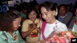 In Myanmar, also known as Burma, opposition leader Aung San Suu Kyi, right, receives flowers from supporters of her National League for Democracy Party, Yangon International Airport, June 10, 2015.
