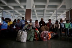 Indian migrant workers wait with their belongings inside a railway station to board trains to their home states following attacks on migrant laborers by suspected militants in Kashmir, on the outskirts of Srinagar, October 18, 2021.