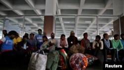 印度移民工人带着自己的行李在火车站站台等车返乡。资料照