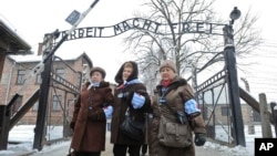 FILE - Holocaust survivors walk outside the gate of the Auschwitz Nazi death camp in Oswiecim, Poland, Jan. 27, 2015. 
