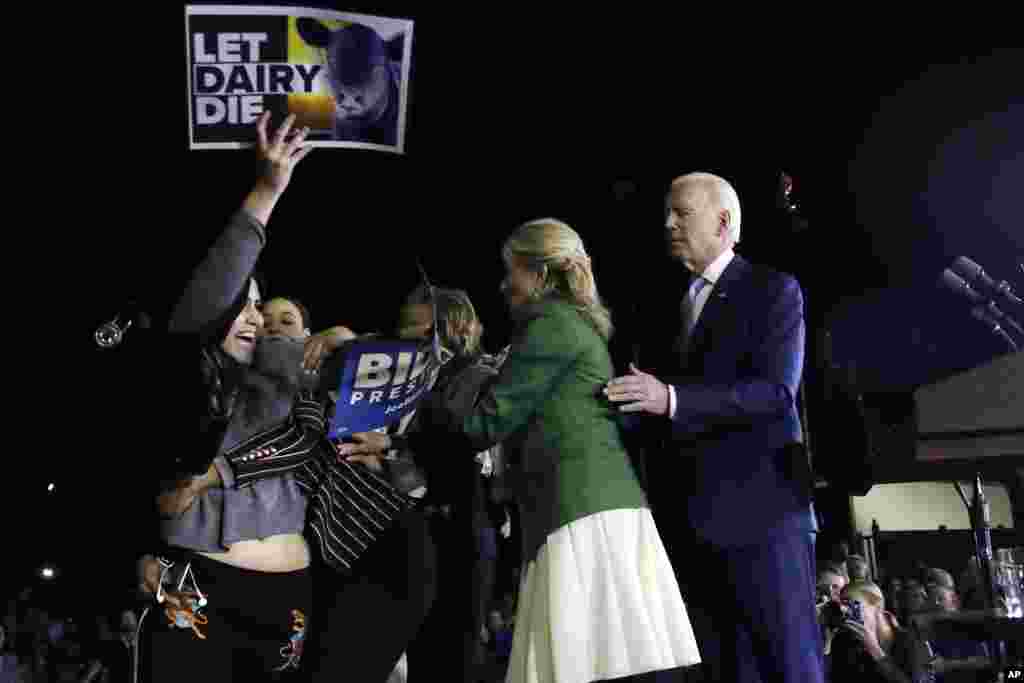 A protester, left, is held back by Biden&#39;s adviser Symone Sanders, wearing stripes, and his wife Jill Biden, second from right, as Democratic presidential candidate former Vice President Joe Biden stands, at right, during a primary election night rally in Los Angeles, California, March 3, 2020.