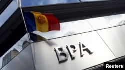 FILE - An Andorran national flag flies next to a Banca Privada d'Andorra (BPA) office in Andorra la Vella, March 29, 2015. 