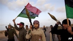 Libyan rebels who are part of the forces against Libyan leader Moammar Gadhafi stand on a road as they secure an area outside the village of Bin Jawwad, west of the recently captured oil town of Ras Lanuf, eastern Libya, March 5, 2011