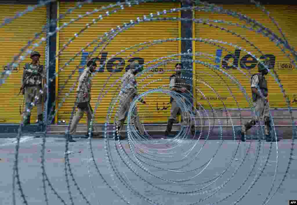 Indian paramilitary and police patrol near a barbed wire fence during a curfew imposed on the Kashmiri summer capital in Srinagar. Indian-administered Kashmir&#39;s main city was under curfew after Indian paramilitary forces on Thursday shot dead six people protesting at a raid by troops on an Islamic school.