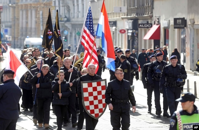 FILE - A group of right-wing radicals wave Croatian and U.S. flags as they march through downtown Zagreb, Feb. 26, 2017.
