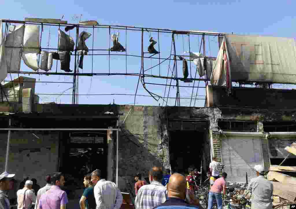People inspect buildings damaged by an Iraqi government airstrike in the northern city of Mosul, Iraq, June 28, 2014.