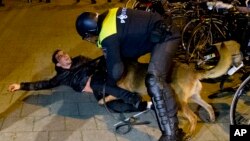 A Dutch riot policeman tries to get his dog to let go of a man after riots broke out during a pro-Erdogan demonstration at the Turkish consulate in Rotterdam, Netherlands, March 12, 2017.