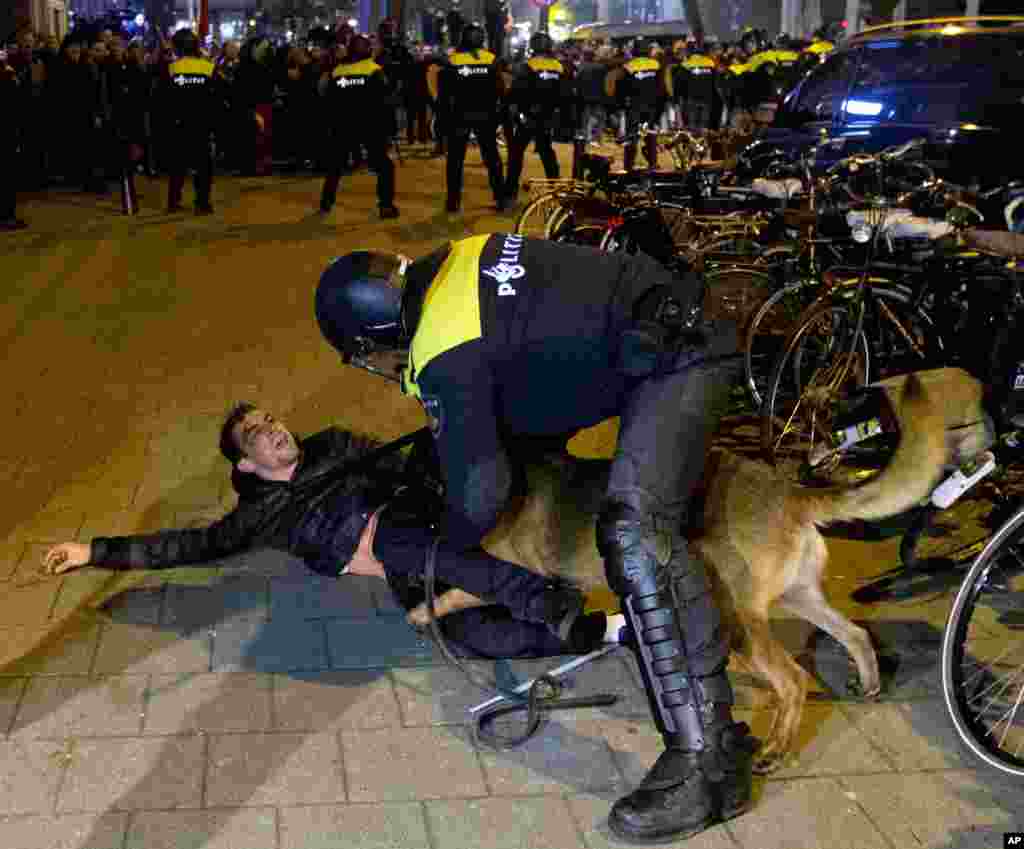 A Dutch riot policeman tries to get his dog to let go of a man after riots broke out during a pro-Erdogan demonstration at the Turkish consulate in Rotterdam, Netherlands, March 12, 2017. 