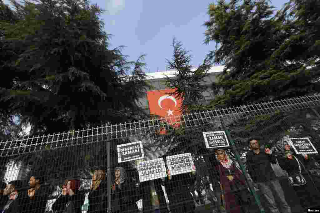 Zaman media group employees and their relatives hold protest signs outside the headquarters of the Zaman daily newspaper in Istanbul, Turkey, Dec. 14, 2014.