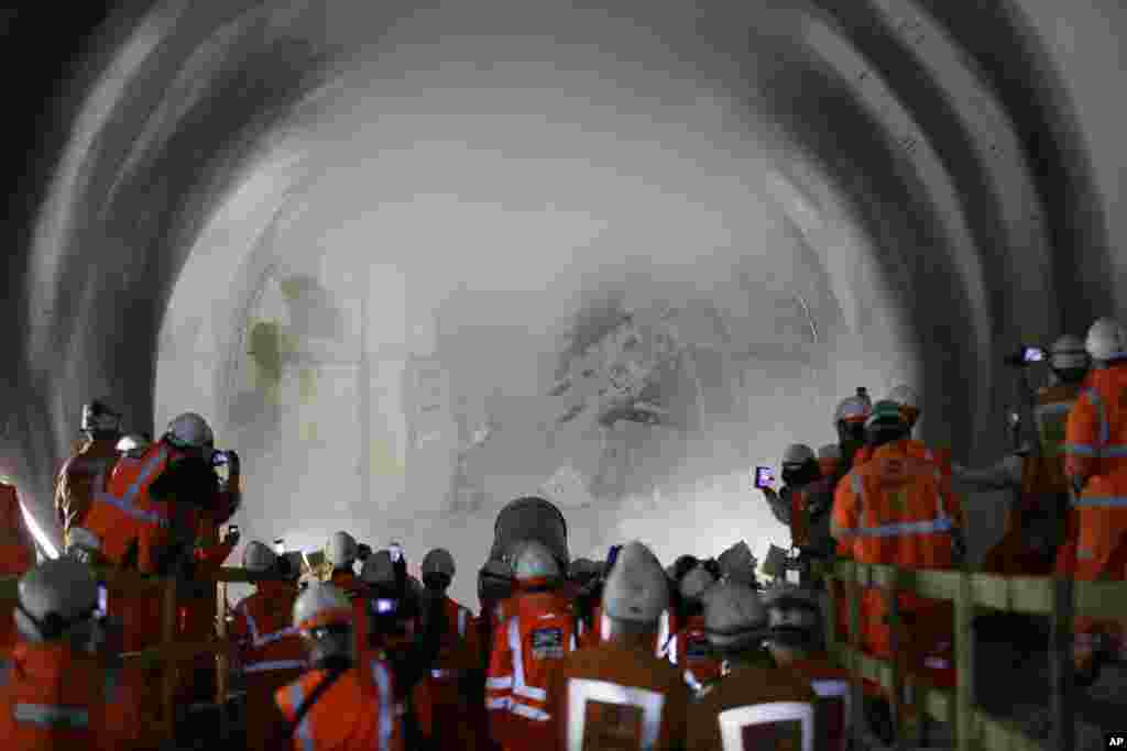 Workers watch and take pictures as a tunnel boring machine Victoria breaks into the eastern end of the Liverpool Street Crossrail station in London.