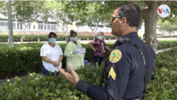 Un agente de policía de la ciudad de Miami explica a las personas que no van a poder recibir comida porque no tienen automóvil.