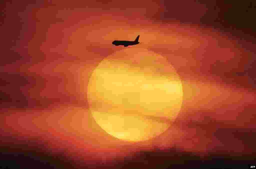 یک هواپیما در حال پرواز در لحظه غروب آفتاب در آسمان شهر جاکارتای اندونیزیا.