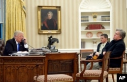 President Donald Trump speaks on the phone with Australian Prime Minister Malcolm Turnbull, with national security adviser Michael Flynn, center, and chief strategist Steve Bannon, right, in the Oval Office of the White House in Washington, Jan. 28, 2017.