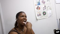 Robin Reese, 41, of Washington, uses an oral test for HIV in front of a poster detailing facts about HIV/AIDS in southeast Washington, June 27, 2012.
