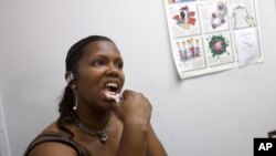 FILE - In this photo taken June 27, 2012, Robin Reese, 41, of Washington, uses an oral test for HIV.