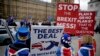 FILE - Anti-Brexit remain in the European Union supporter Steve Bray, left, holds placards as he demonstrates with others opposite the Houses of Parliament in London, Jan. 21, 2019. 