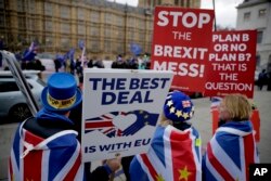 Anti-Brexit remain in the European Union supporter Steve Bray, left, holds placards as he demonstrates with others opposite the Houses of Parliament in London, Jan. 21, 2019.