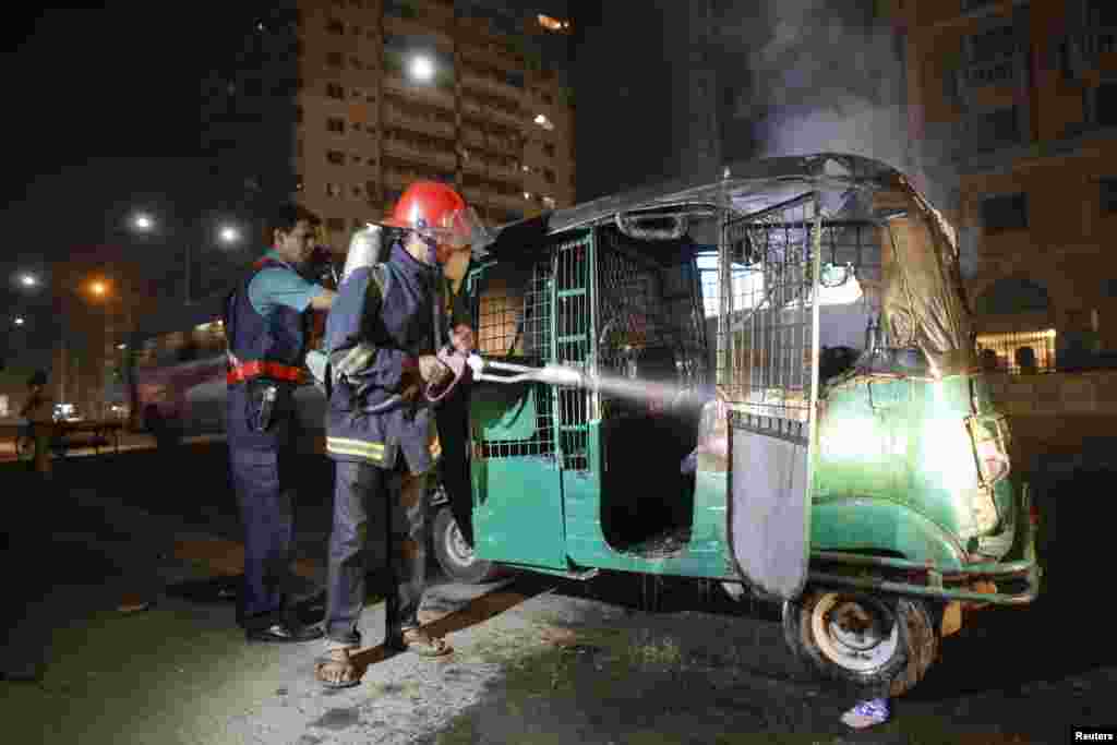 A firefighter and a police officer extinguish a fire on an auto rickshaw in Dhaka, Nov. 25, 2013. 