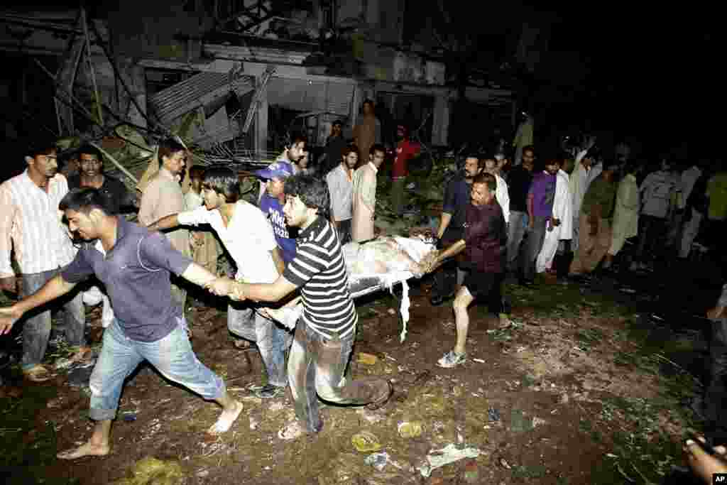 人们2013年3月3日在巴基斯坦你卡拉奇一枚炸弹爆炸现场将一名遇难者的尸体抬出来。