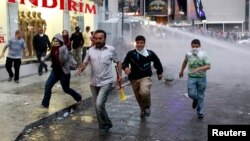 Demonstran anti-pemerintah di Ankara berlari melindungi diri dari semburan meriam air dan gas air mata seiring upaya polisi membubarkan mereka (5/6). (Reuters/Umit Bektas)