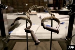FILE - A pair of slave shackles are on display in the Slavery and Freedom Gallery in the Smithsonian's National Museum of African American History and Culture during the press preview on the National Mall in Washington, D.C., Sept. 14, 2016.