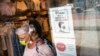 Seorang pelanggan yang mengenakan masker keluar dari toko di Broadway di distrik perbelanjaan ritel di lingkungan SoHo di wilayah Manhattan, New York, Jumat, 14 Mei 2021.. (Foto: AP)