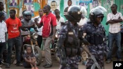 Ugandan riot police stand close to dejected opposition supporters to prevent them from demonstrating, shortly after the election result was announced, in downtown Kampala, Uganda, Feb. 20, 2016. 