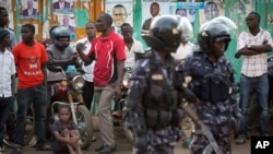 FILE - Ugandan riot police stand close to dejected opposition supporters to prevent them from demonstrating, shortly after the election result was announced, in downtown Kampala, Uganda, Feb. 20, 2016. 