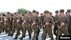 Soldiers gather to offer flowers to the statues of state founder Kim Il Sung and former leader Kim Jong Il on the Day of Songun at Mansu hill, Pyongyang, North Korea, in this undated photo released by North Korea's Korean Central News Agency, Aug. 26, 201