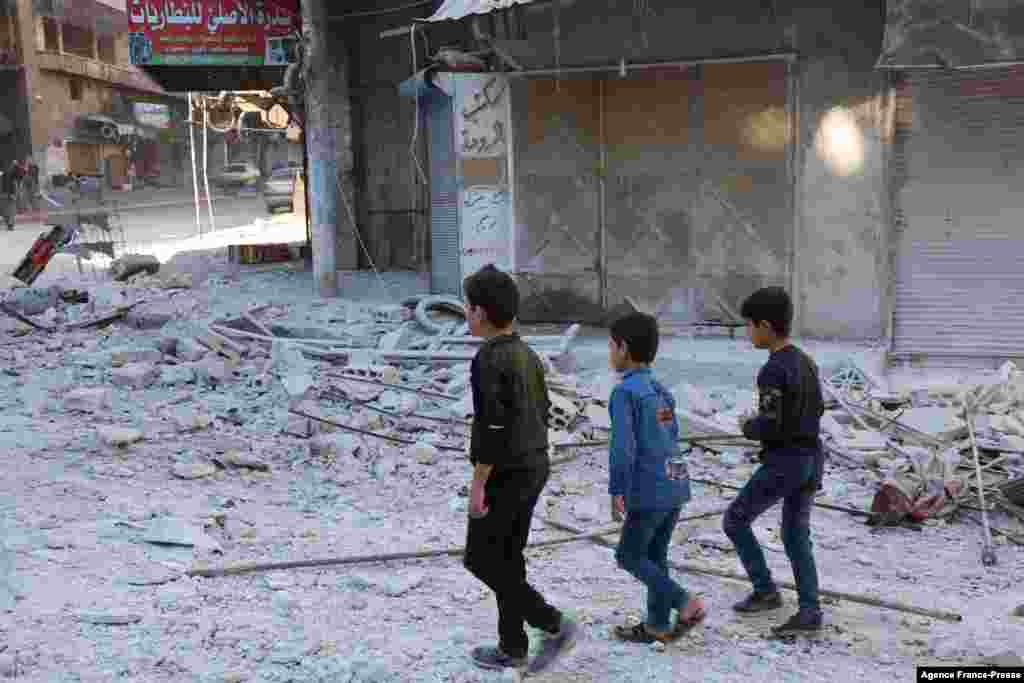 People walk past debris at the site of shelling in the Syrian town of Ariha in the rebel-held northwestern Idlib province.