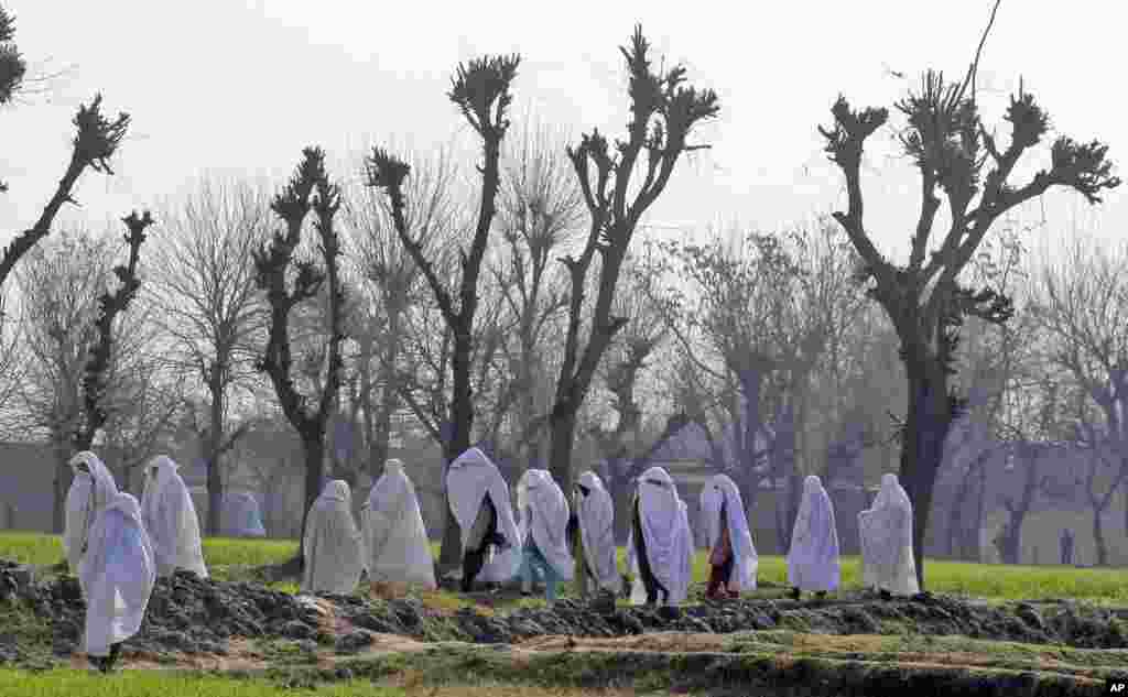 Women walk near the site of an attack on the outskirts of Peshawar, Pakistan. Militants killed several members of an anti-Taliban militia in country's northwestern city, police said.