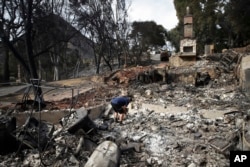 Roger Kelton searches through the remains of his mother-in-law's home leveled by the Woolsey Fire, Nov. 13, 2018, in the southern California city of Agoura Hills.