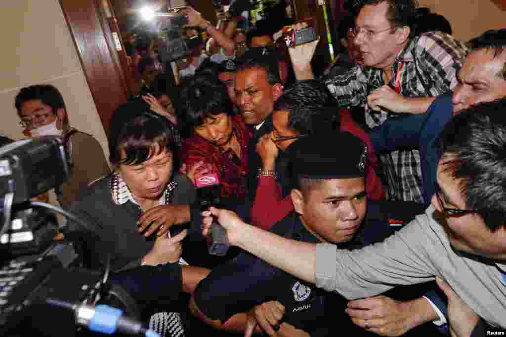 A Chinese family member of a missing Malaysia Airlines MH370 passenger is escorted away from the media outside the media conference area at a hotel near Kuala Lumpur International Airport, March 19, 2014.