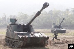 ທະຫານຄົນນຶ່ງແລ່ນໄປຫາລົດຫູ້ມເກາະ M109 ລະຫວ່າງການເຝິກຊ້ອມທີ່ເຂດ Chukeng ໃນເມືອງ Taichung ໄຕ້ຫວັນ.