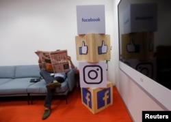 FILE - A man reads a newspaper at the reception area of Facebook's new office in Mumbai, India, May 27, 2016.