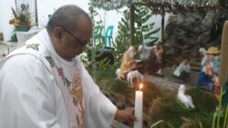 Pastor Joy Derry memasang lilin di depan kandang natal dalam misa malam Natal di gereja Katolik stasi Sidera, Sigi, Sulawesi Tengah (24/12) Foto : VOA/Yoanes Litha