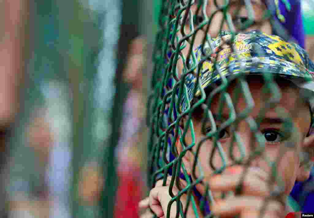 A Kashmiri child looks from behind a fence at a the site of a demonstration in Srinagar to protest of the Indian government&#39;s decision to cancel the area&#39;s special constitutional status.