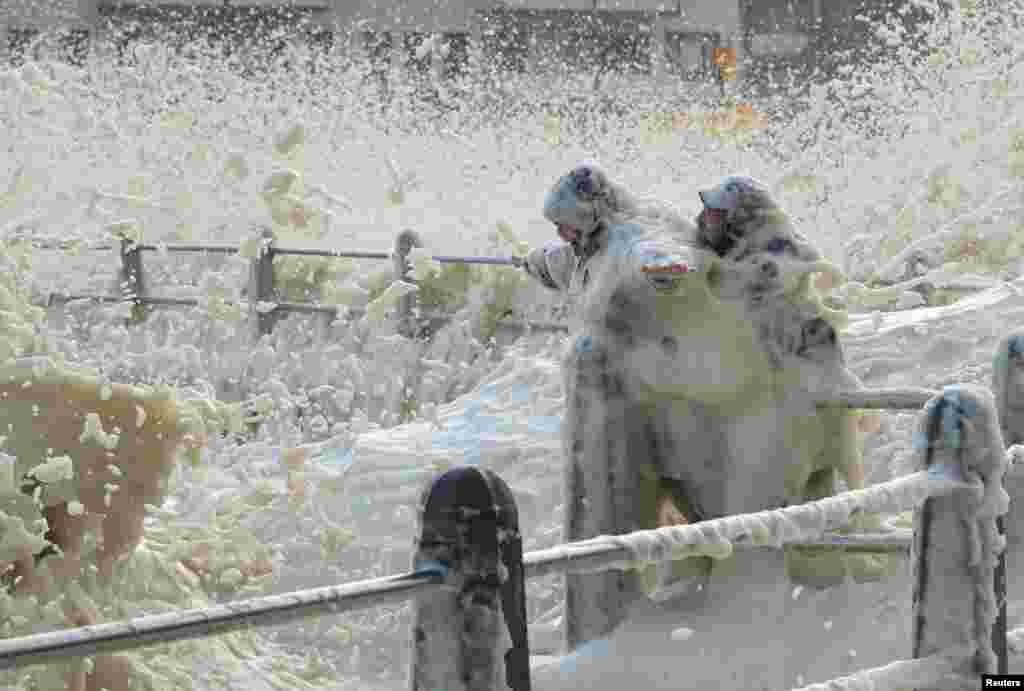 People are drenched by sea spray thrown up by huge swells as a cold front moves in over Cape Town, South Africa.