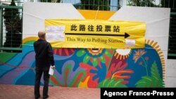 A man looks at a banner outside a polling station during the Legislative Council election in Hong Kong's Hung Hom area, Dec. 19, 2021. 