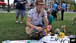 Johnathan Dalton breaks down as he places flowers on a makeshift memorial, Monday, June 13, 2016 in memory of two of his friends who were killed during a fatal shooting at the Pulse Orlando nightclub in Orlando, Fla. (AP Photo/Chris O'Meara)