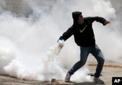A Palestininan throws back a tear gas cannister during clashes on Nakba Day near Hebron.